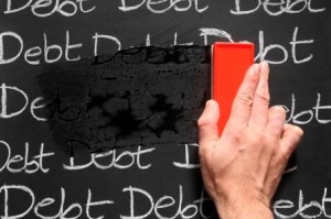 An hand erasing the words "debt" written several times on a blackboard