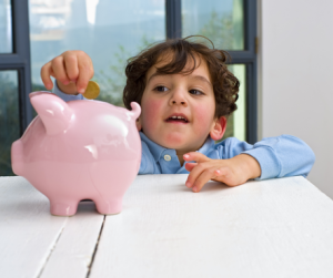 A kid filling a pig money box with a coin